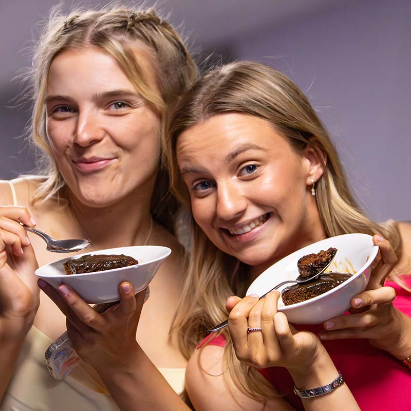 Two students smiling with desserts