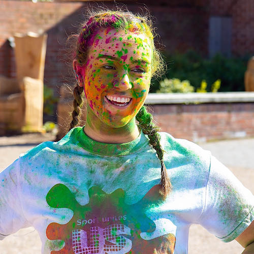 A smiling student covered in colourful paint