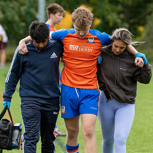 An injured sports member being helped from the pitch